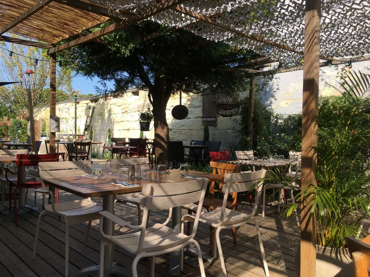La terrasse ombragée, tables dressées sous les arbres